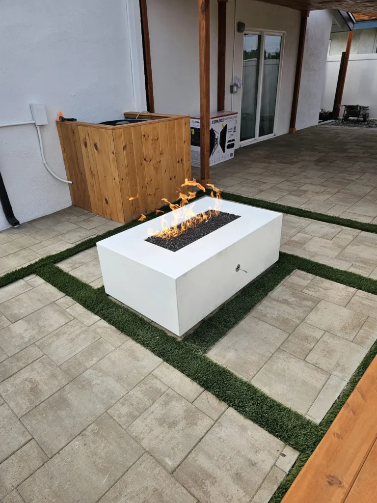 Backyard with a modern fire pit set in turf and stone pavers, remodeled by DC Home Renovations in Los Angeles.