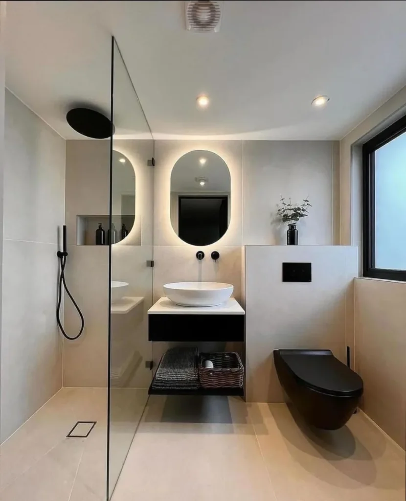 Modern bathroom with a glass shower, oval mirror, vessel sink, and black vanity, remodeled by DC Home Renovations in Los Angeles.