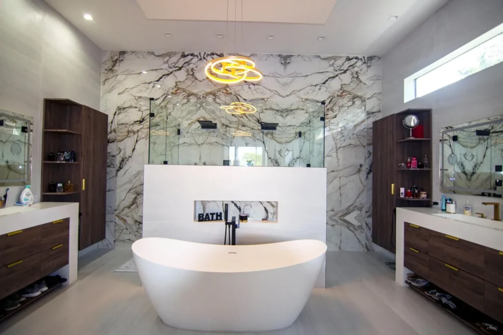Luxury bathroom with a marble feature wall, freestanding tub, and gold pendant, remodeled by DC Home Renovations in Los Angeles.