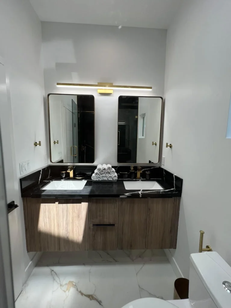 Bathroom with a floating vanity, dark stone counter, and dual mirrors, remodeled by DC Home Renovations in Los Angeles.