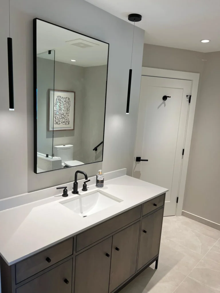 Bathroom with a wood vanity, framed mirror, and matte black fixtures, remodeled by DC Home Renovations in Los Angeles.