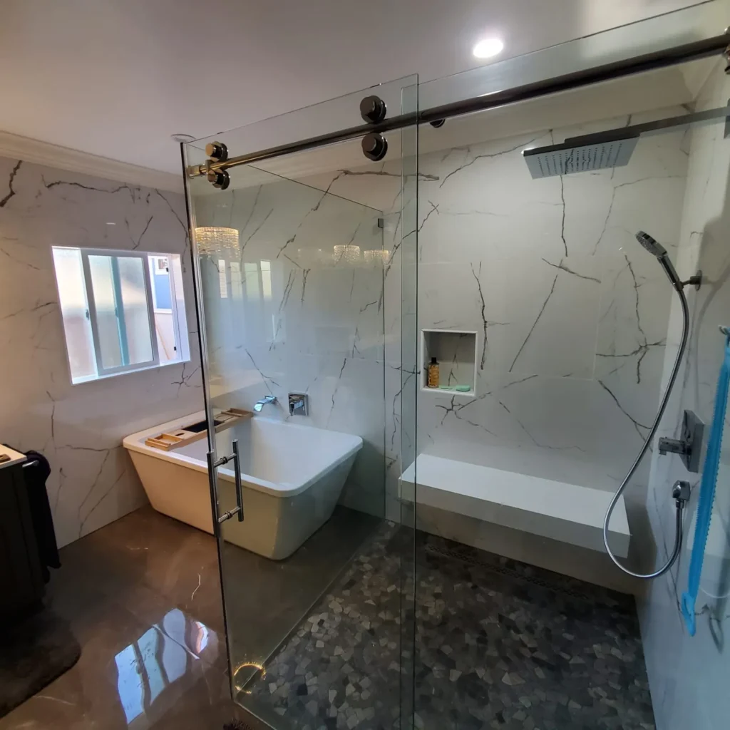 Bathroom with a freestanding tub and a marble walk-in shower by a window, remodeled by DC Home Renovations in Los Angeles.