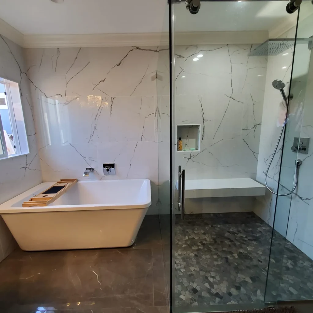 Bathroom with a freestanding tub and a bookmatched marble walk-in shower, remodeled by DC Home Renovations in Los Angeles.