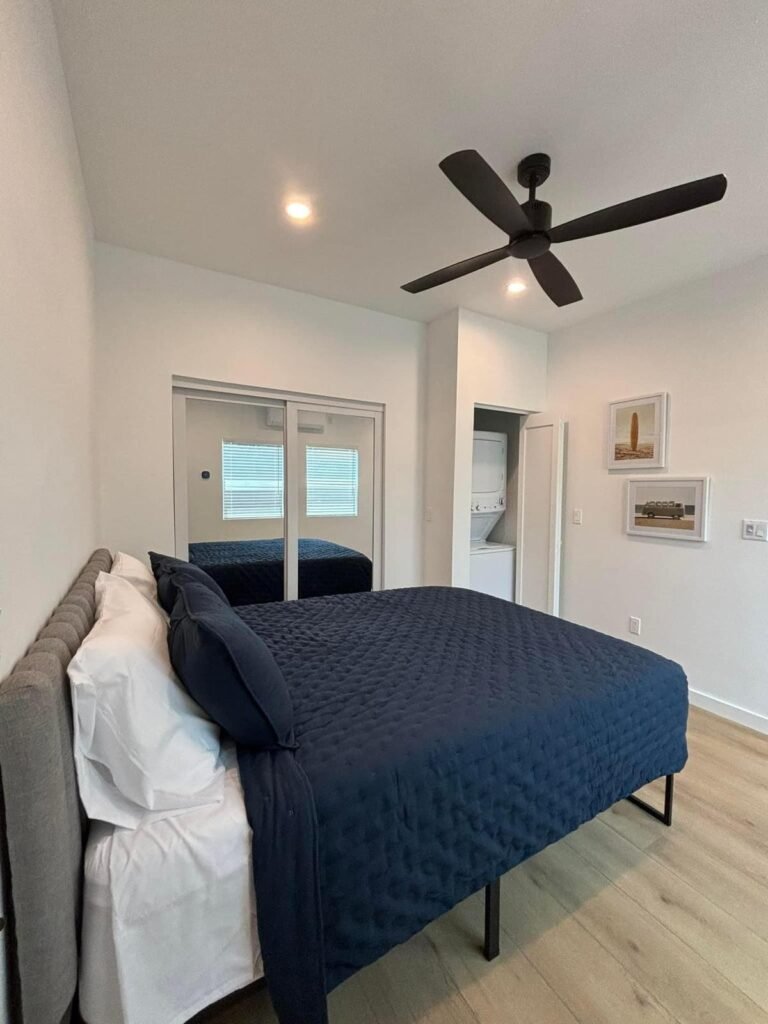 Modern bedroom remodel in Orange County featuring luxury vinyl plank flooring, recessed lighting, black ceiling fan, mirrored closet doors, and fresh interior paint.
