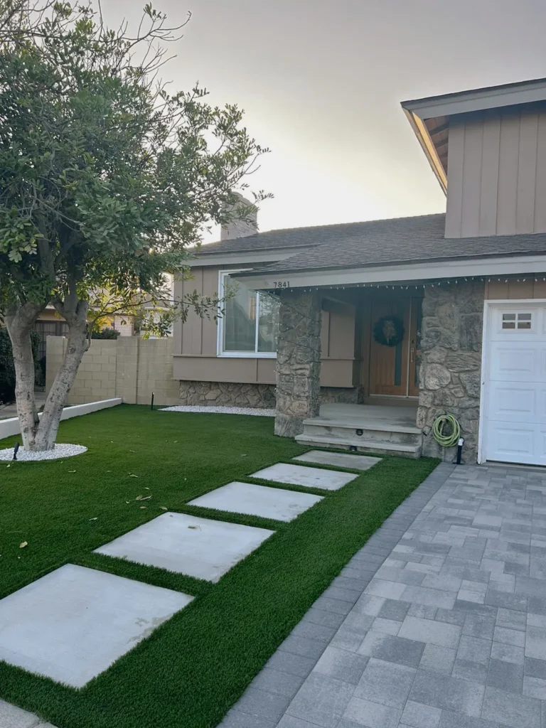 Renovated home exterior at dusk with a stone facade and a landscaped path, remodeled by DC Home Renovations in Los Angeles.