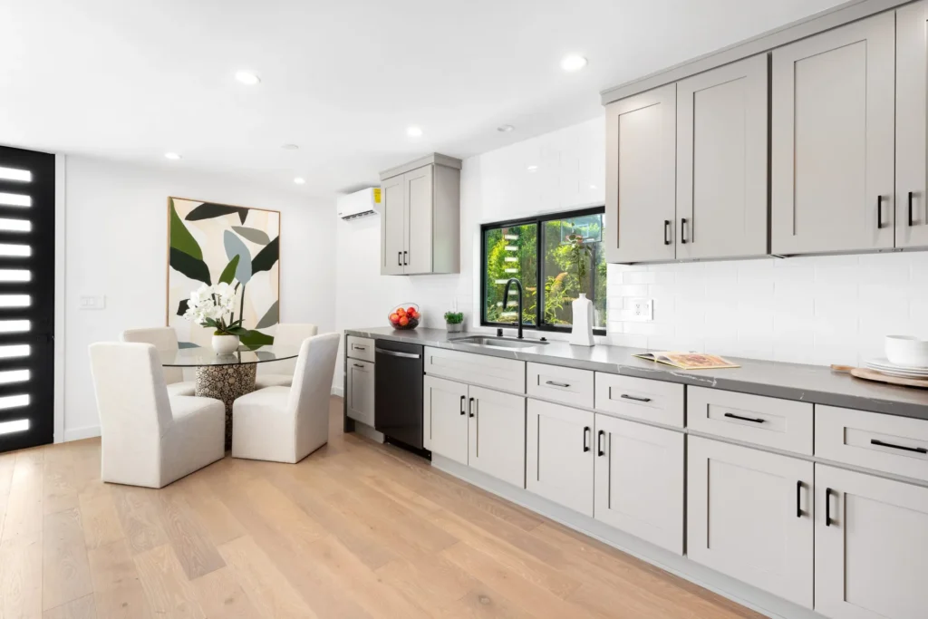 White kitchen with a breakfast nook, black-framed windows, and open shelving, remodeled by DC Home Renovations in Los Angeles.