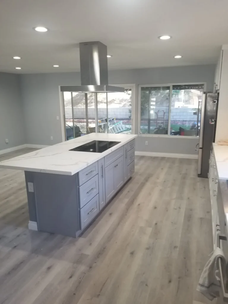 Open kitchen with a marble waterfall island and a wall of windows, remodeled by DC Home Renovations in Los Angeles.