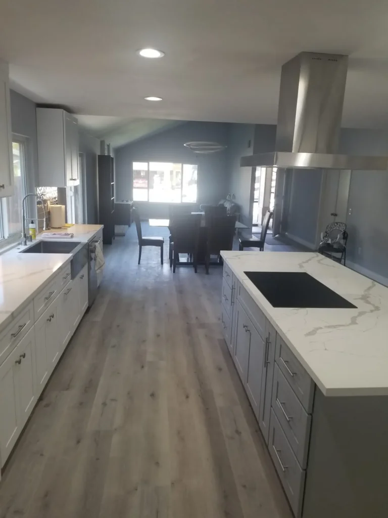 Modern kitchen with a marble island, stainless range hood, and open dining area, remodeled by DC Home Renovations in Los Angeles.