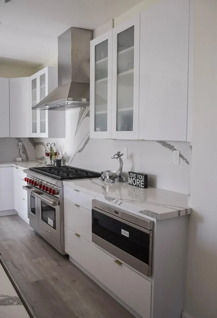 White kitchen with a professional range and a marble slab backsplash, remodeled by DC Home Renovations in Los Angeles.