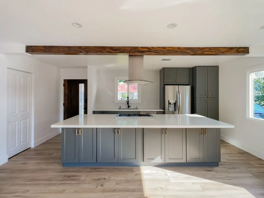 Kitchen with a gray island, a reclaimed wood beam, and stainless appliances, remodeled by DC Home Renovations in Los Angeles.