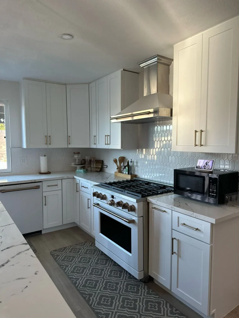 White kitchen with a gas range, marble backsplash, and stainless appliances, remodeled by DC Home Renovations in Los Angeles.